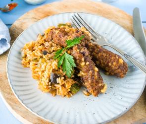 Ein Teller, angerichtet mit Cevapcici und Gemüsereis.