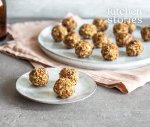Mehrere Energiekugeln mit Datteln und Honig auf zwei Tellern.