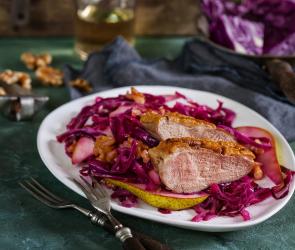 Gebratene Entenbrust mit lauwarmem Birnen-Rotkohlsalat auf einem Teller.