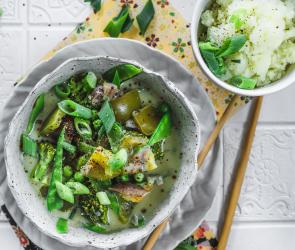 Grünes Kokos-Gemüse-Curry mit Blumenkohlreis in einem Teller.