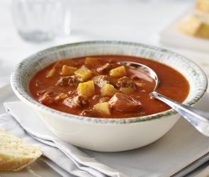 Gulaschsuppe in einem Suppenteller angerichtet.