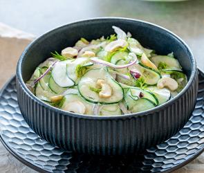 Gurkensalat mit Sellerie in einer Schüssel auf einem Tisch.