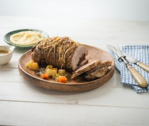 Kalbsrollbraten mit Kräuterfüllung und Gemüse auf einem Teller.