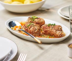 Kalbsrouladen mit Gorgonzolacreme gefüllt auf einem Teller auf einem gedeckten Tisch.