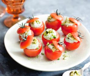 Ein Teller mit gefüllten Tomaten mit Basilikumcreme.