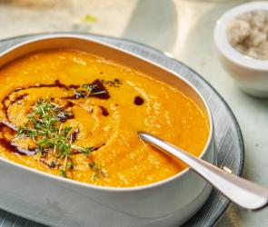 Kürbis-Curry-Suppe mit Kürbiskernöl in einem Teller angerichtet.