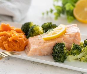Lachs, gedämpft mit Süßkartoffelpüree und Brokkoli auf einem Teller angerichtet.