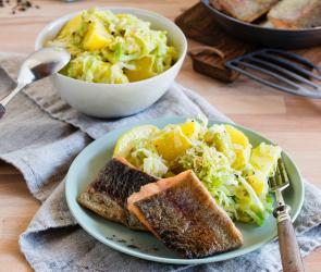 Lachsforelle auf Kartoffel-Spitzkohl-Gemüse auf zwei Tellern angerichtet.