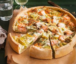 Lauchquiche mit Lachs angeschnitten auf einem Brett.