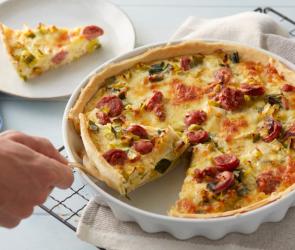 Ein Stück Lauchquiche wird aus einer Form gehoben.