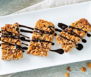Müsliriegel mit Kokosnuss und Mandeln und Schoko auf einem Teller.