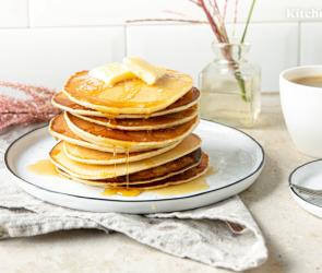 Pancakes amerikanisch übereinander gestapelt mit Butter und Sirup auf einem Teller.
