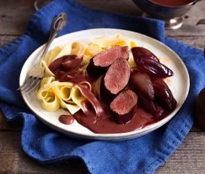 Rehfilet auf einem Nudelbett und roter Sauce.