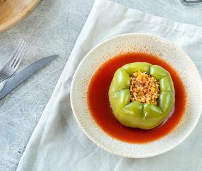 Paprikaschoten gefüllt mit Blumenkohl und Linsen auf Tomatensoße in einem Teller.