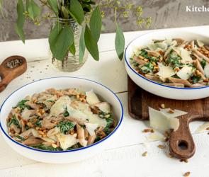 Penne mit Ziegenfrischkäse und Spinatsoße auf zwei Tellern angerichtet.