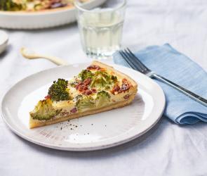 Quiche Lorraine mit Brokkoli als Stück auf einem Teller.