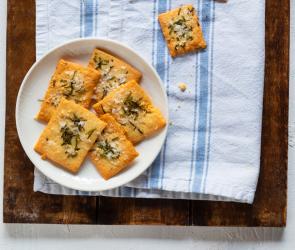 Rosmarin-Cracker auf einem Teller mit Kräutern angerichtet.