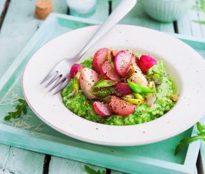 Rucolarisotto mit karamellisiertem Frühlingszwiebel-Radieschen-Gemüse in einem tiefen Teller angerichtet.