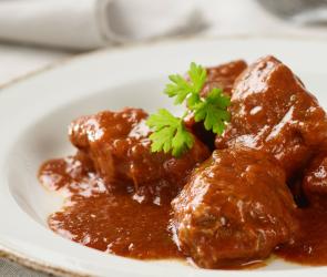 Saftgulasch nach Wiener Art auf weißem Teller mit Petersilie garniert.