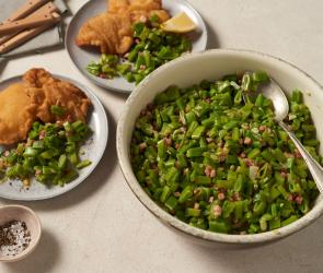 Salat mit grünen Bohnen in einer großen Schalen und auf einem Teller mit Schnitzel.