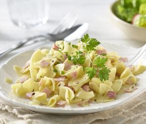 Schinkenfleckerl auf einem Teller mit Petersilie angerichtet.