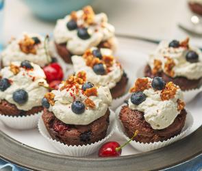 Viele Schoko-Muffins mit Früchten Chili und Sahnehaube auf einem Teller.