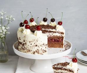Torte auf Tortenplatte mit Vase und Kuchenstück auf Teller