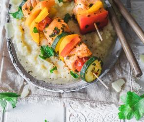 Selleriepüree mit Lachs-Gemüse-Spießen auf einem Teller angerichtet.