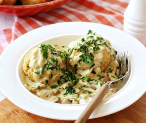 Semmelknödel mit Pilzrahm auf einem Teller mit Besteck.