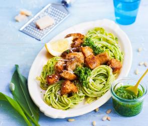 Spaghettini mit Bärlauchpesto und gebratenem Hähnchen auf einem Servierteller.