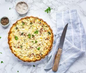 Spinat-Speck-Quiche auf einem Tisch.