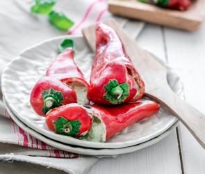 Drei gefüllte Spitzpaprikas auf einem Teller.