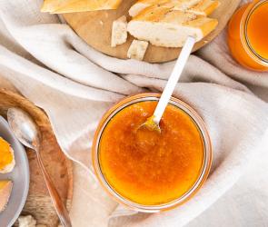 Süße Kürbismarmelade auf einem Brot neben Käse auf einer Platte.