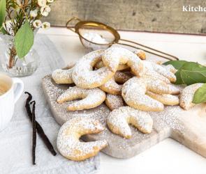 Mehrere Vanillekipferl auf einem Holzbrett.