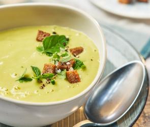 Zucchini-Kartoffel-Suppe in einem Teller mit Brotcroûtons garniert.