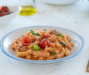 Pasta mit Thunfisch, Tomaten und Zitrone im tiefen Teller.