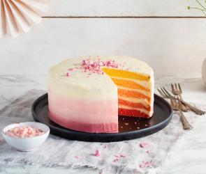 Rosa Ombré-Cake Zitrone-Joghurt-Creme angeschnitten auf einem Servierteller.