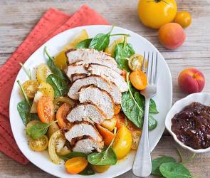 Gelber Sommersalat mit gegrillter Hähnchenbrust Sous-vide und Schalottenchutney auf einem Teller angerichtet.