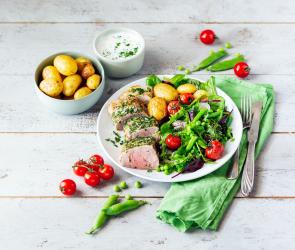 Kräuter-Schweinefilet mit Ofenkartoffeln und Bohnensalat auf einem Teller.