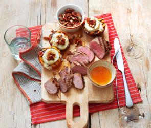 Lammlachs vom Grill mit Ziegenkäse-Nektarinen (Sous-vide) auf einem Holzbrett.