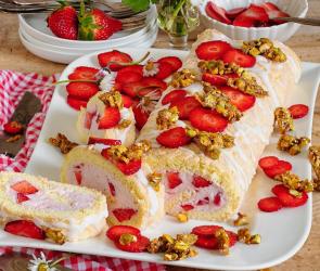 Biskuitrolle mit cremiger Erdbeerfüllung auf einem Servierteller.