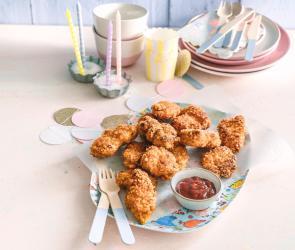 Chicken Nuggets auf einem Teller vor Partydekoration.