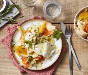 Fisch mit Gemüse und Orangenfilets auf einem Teller-