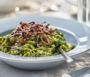 Grüne Käsespätzle mit Röstzwiebeln auf einem Teller.