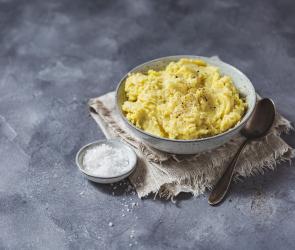 Eine Schüssel mit Kartoffelpüree mit Löffel und Salt daneben.