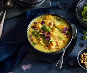 Gelbes Süßkartoffelcurry mit Kräutern in einer Schüssel.