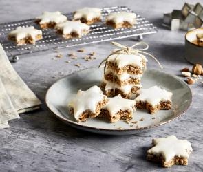 Zimtsterne auf eine Kuchengitter und grünem Teller.