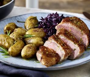 Entenbrust mit Rosmarin-Kartoffeln und Rotkohl auf einem Teller.
