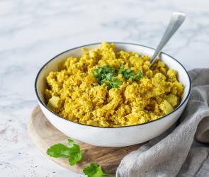 Rührei mit Petersilie in einer hellen Schale auf einem Marmoruntergrund.