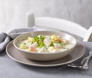 Eintopf mit Lauch, Kartoffeln und Geflügel in einem tiefen Teller.